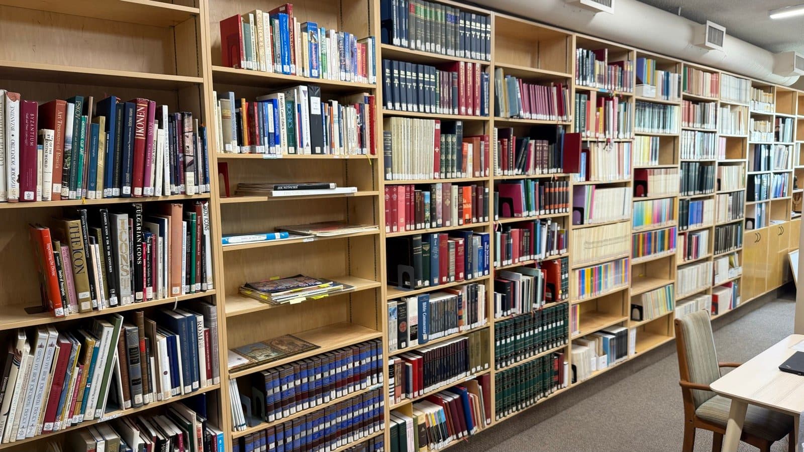 Shelves of theological, historical, and Ukrainian books beside a quiet reading table in the parish library