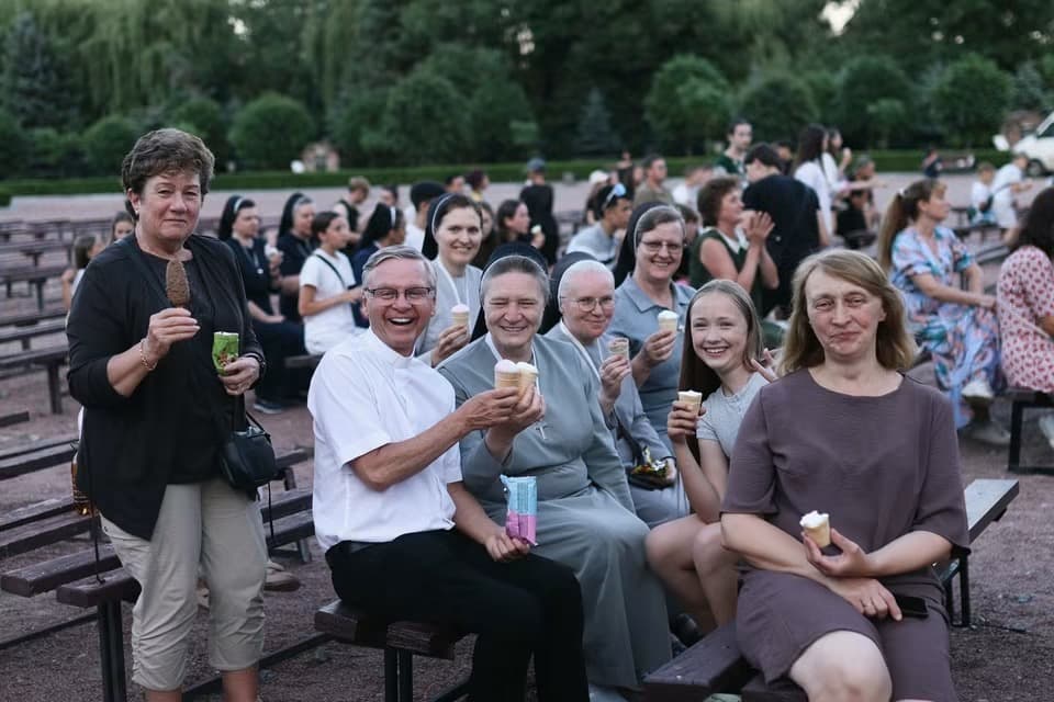 Clergy and sisters enjoy ice cream together outdoors on a warm day.